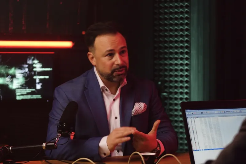 Studio: Mann mit Bart im blauen Sakko spricht am Tisch mit Mikrofon (Francesco Bisignano)